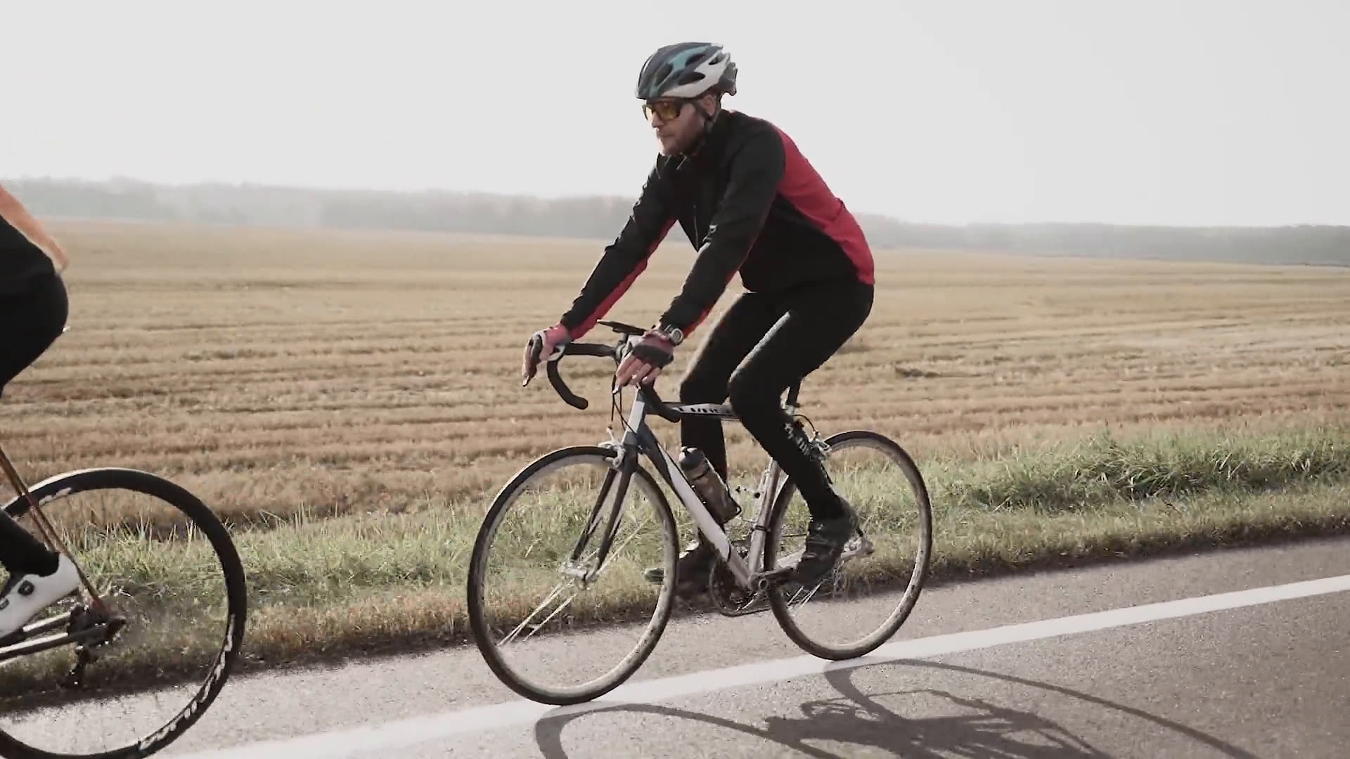 Een fietser alleen op een weg langs de velden